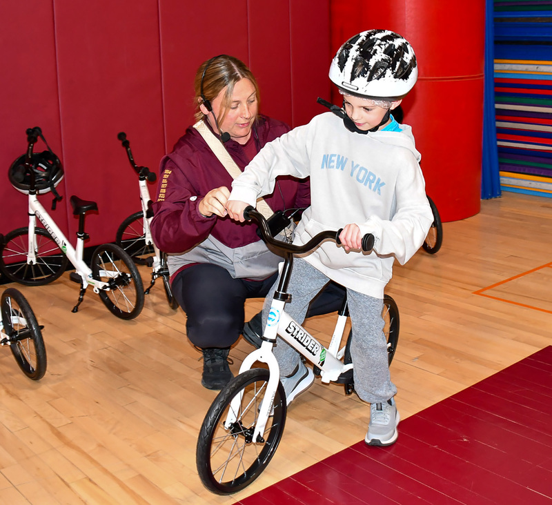 Physical Education teacher Dani Montesano adjusts the seat on a first graders bicycle during a lesson on how to ride.