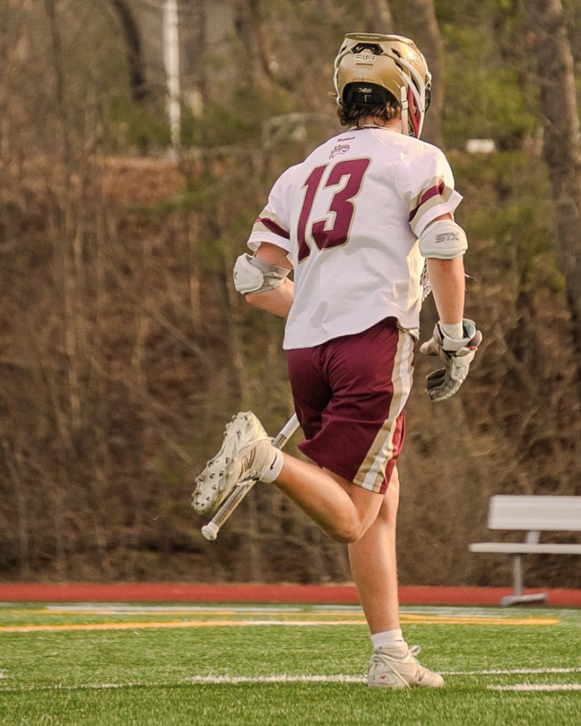 Boys Lacrosse player running on field.