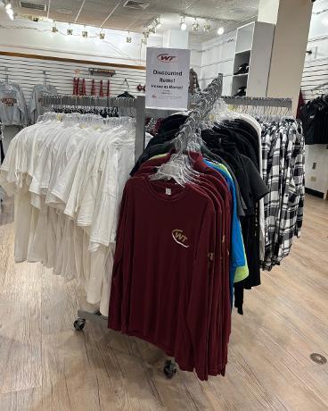 Clothing items displayed in the School Store have reduced prices for the end of the year.