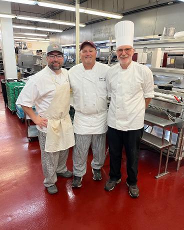 Culinary Arts Instructors Mr. Crovetti, retired Mr. Yameen, and about-to-be-retired Mr. Boringa smiling in the kitchen.