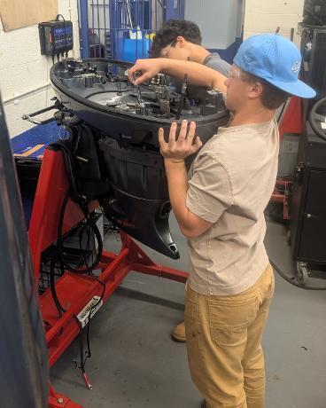 Marine Tech Students working on a boat engine.