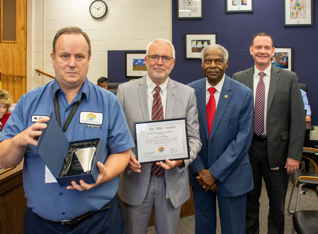 Image of September Extra Mile Award recipient Robert O'Day of James M. Bennett High School with JMB Principal Matthew Donovan, Board Member Allen Brown and Superintendent of Schools, Dr. Micah Stauffer