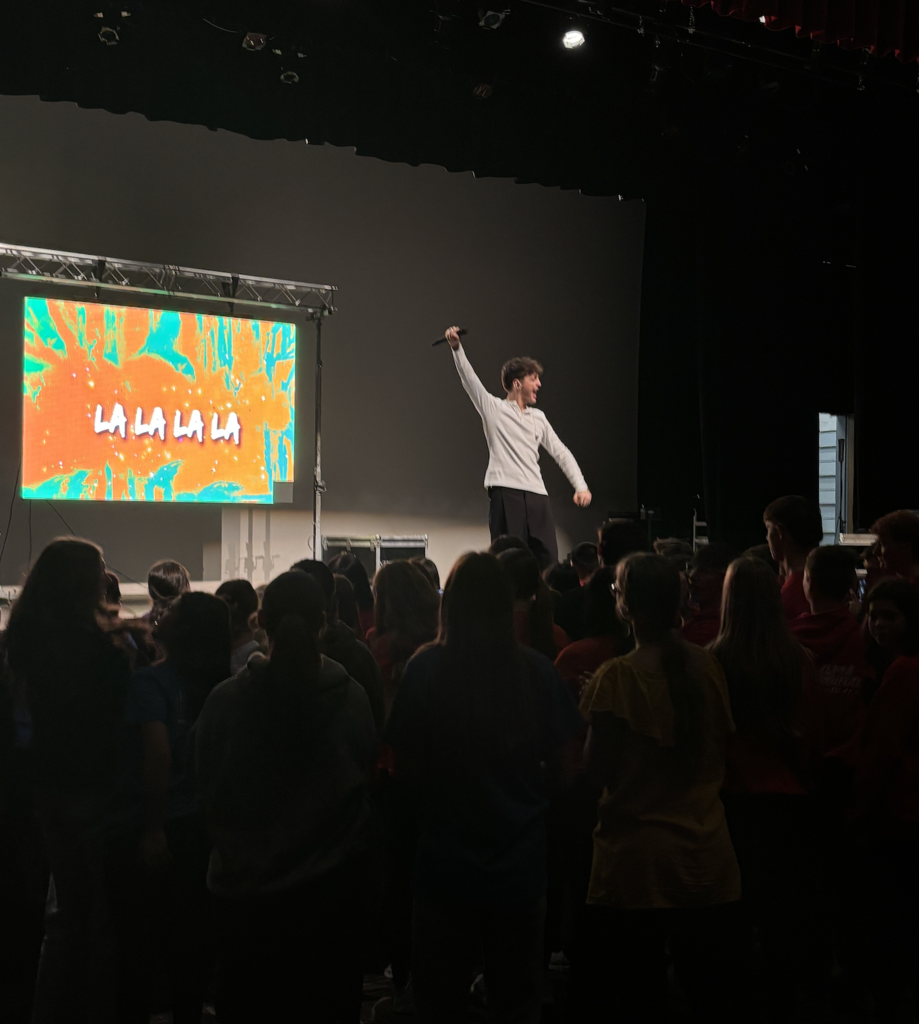 Emanuel singing with students in front of the stage