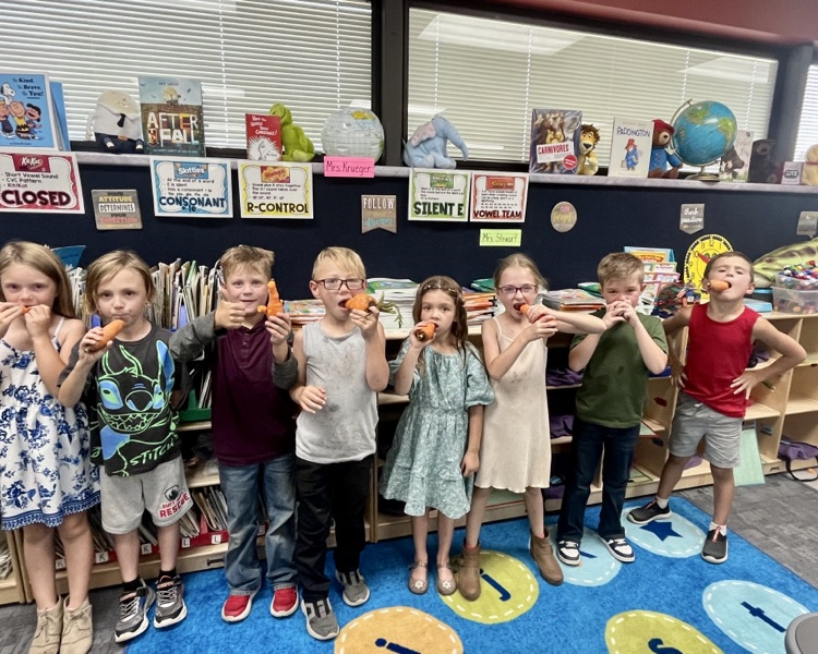 first graders enjoy carrots from garden