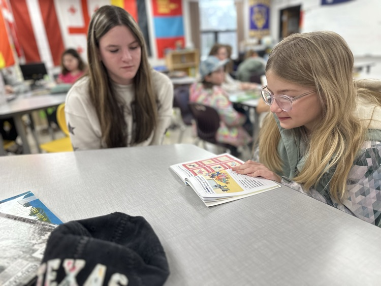Elementary student reading to high school student