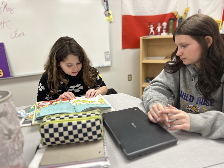 Elementary student reading to high school student