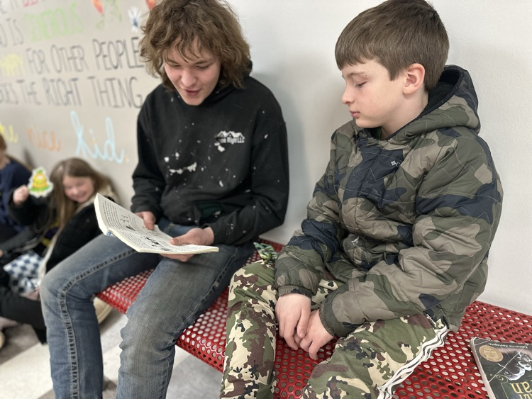 high school student reading to elementary school student