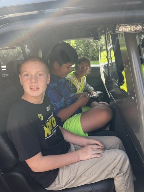 middle school students sit in squad car