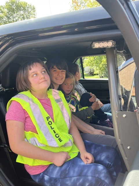 middle school students sit in squad car