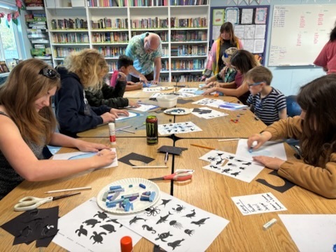 Marisa and Owen leading students in a pastel activity portraying an ecosystem in our world. This is the table focusing on the sea!