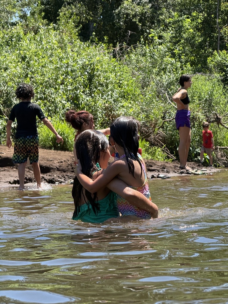 A picture of two students giving each other a hug while swimming in the creek.
