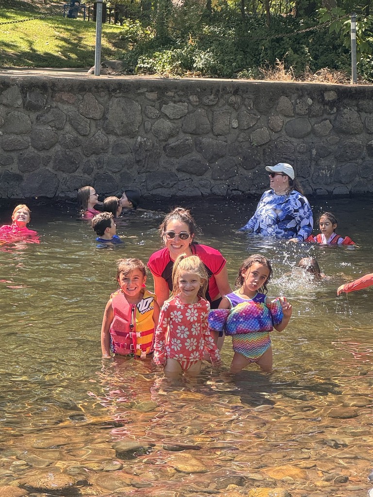 A camp counselor and three students posed for a picture while standing in the creek.