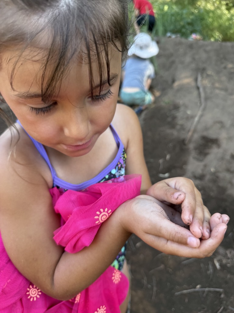 A picture of a camper showing off a frog that she found.