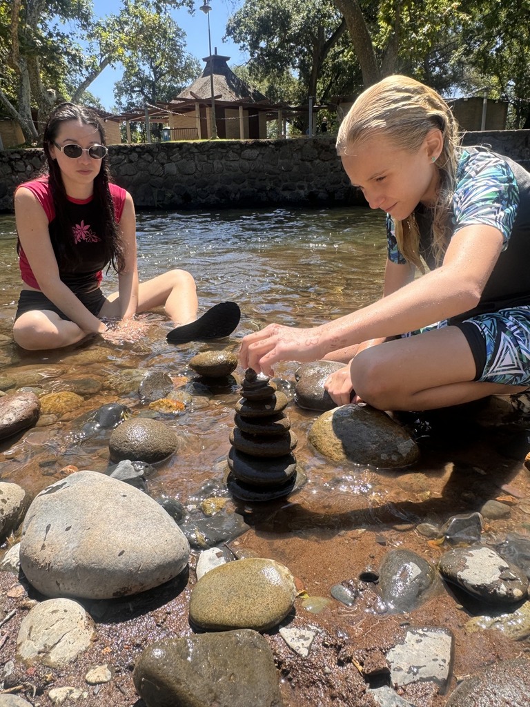One of our students and a camp counselor building a rock tower in the creek.
