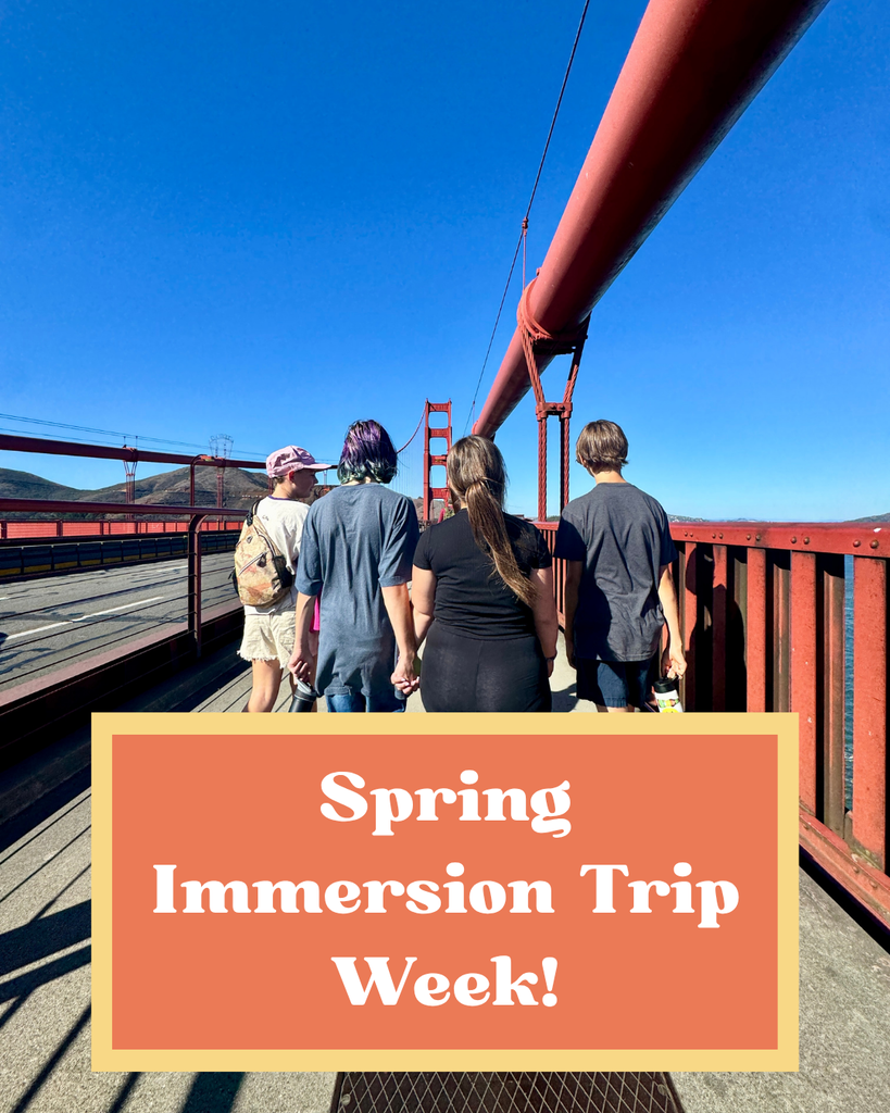 Here is a photo taken behind a group of four students walking across the Golden Gate Bridge. They are walking in a line with one of the arches of the bridge centered ahead of them. In a framed orange and yellow box is text that says "Spring Immersion Trip Week!"