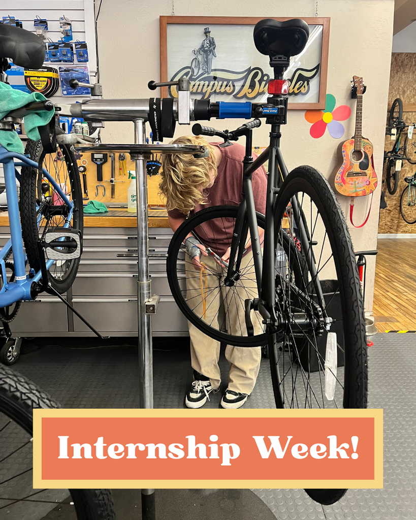Here is a photo of one of our middle school students at his internship at a bike shop. In the photo he is working on the front tire of a bike that has been propped up on the work bench. In an orange and yellow box towards the bottom of the photo is text that says "Internship Week"!