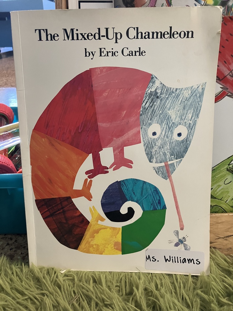 Here is a photo of the book titled "The Mixed-Up Chameleon" by Eric Carle. This book cover is white with a large colorful chameleon drawn in the center of the book. The chameleon has stripes of different colors across his body and his tongue out trying to catch a fly. The title and author name are centered together at the top of the book.