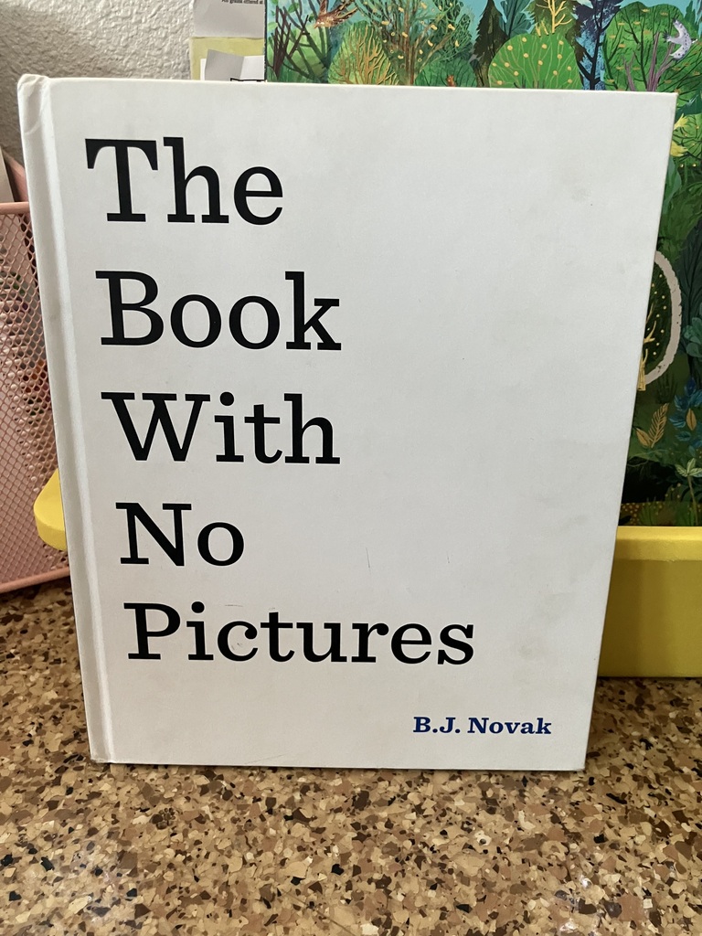 Here is a photo of the book titled "The Book With No Pictures." This book cover is white and the only thing on the front is the title and the author's name in black text. In the bottom right corner is the author's name and lined along the left side of the cover, is the title of the book.