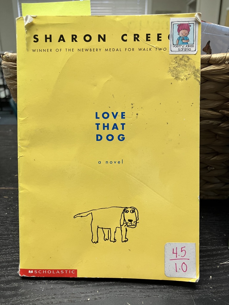 Here is a photo of the book "Love That Dog". The book cover is yellow with the author's name in black writing across the top. In the center of the cover is text that says "Love That Dog" in blue writing. Underneath the writing and centered towards the bottom of the cover is a line drawing of a dog.