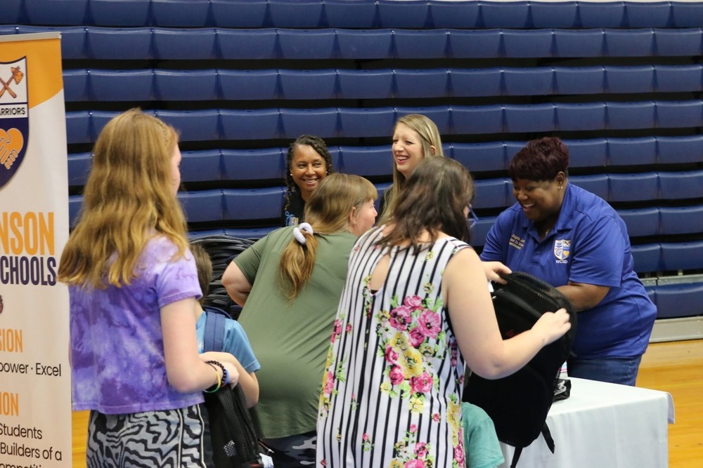 Wilkinson County Schools staff members smile and assist families with backpacks and school supplies during the annual Back-to-School Drive in the school gymnasium.