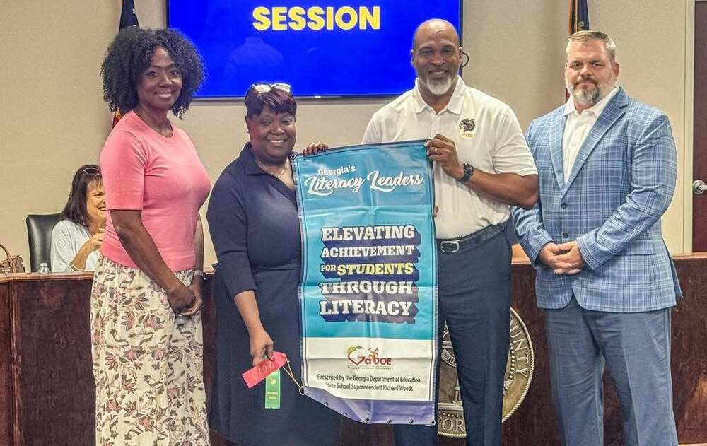 From left, Dr. Latonia Butts, Assistant Principal of Instruction; Superintendent Dr. Angela James; Dr. Jamie Paulk, Principal; and Michael Hussey, Assistant Principal of Operations, display Wilkinson County High School’s Georgia Literacy Leader banner during the August Board of Education meeting.