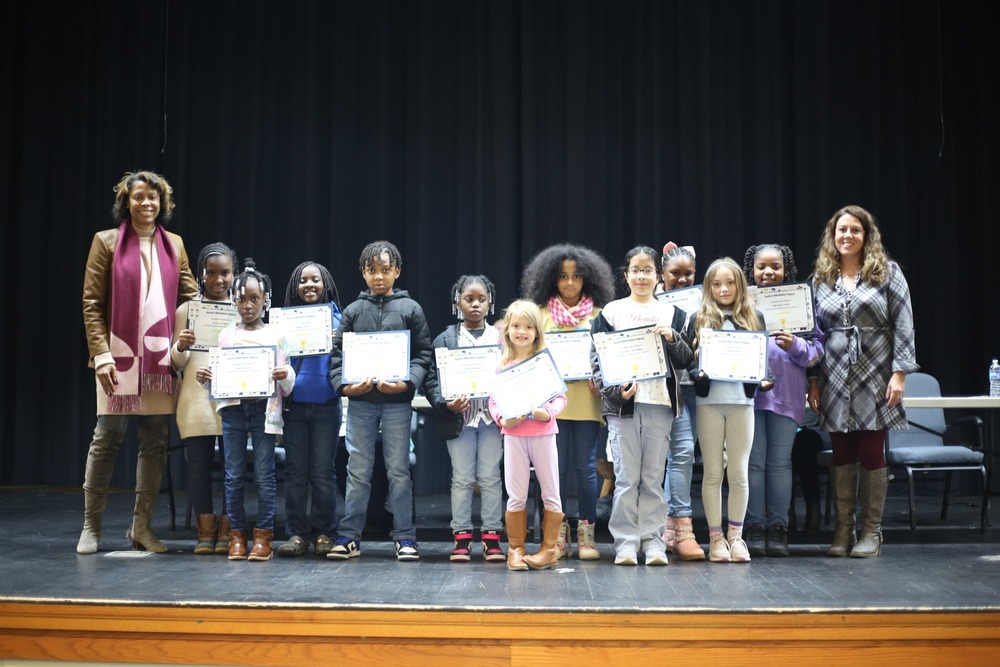 A group of students from various grade levels pose together holding their perfect attendance certificates.