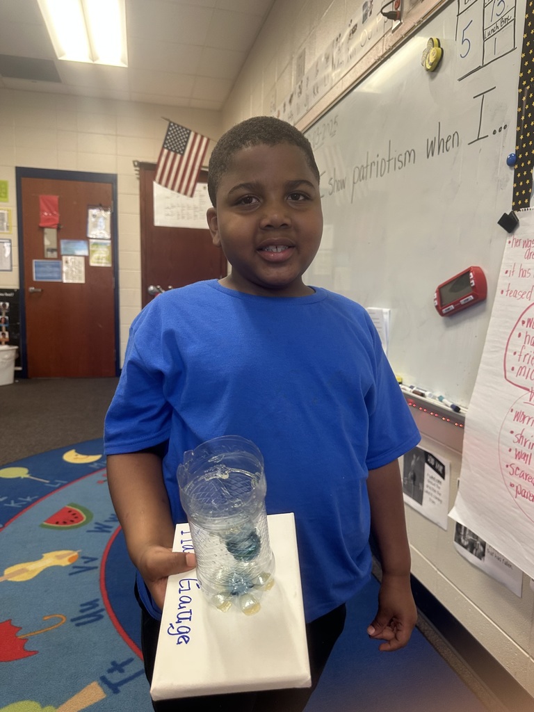 student holding rain gauge made out of a plastic bottle