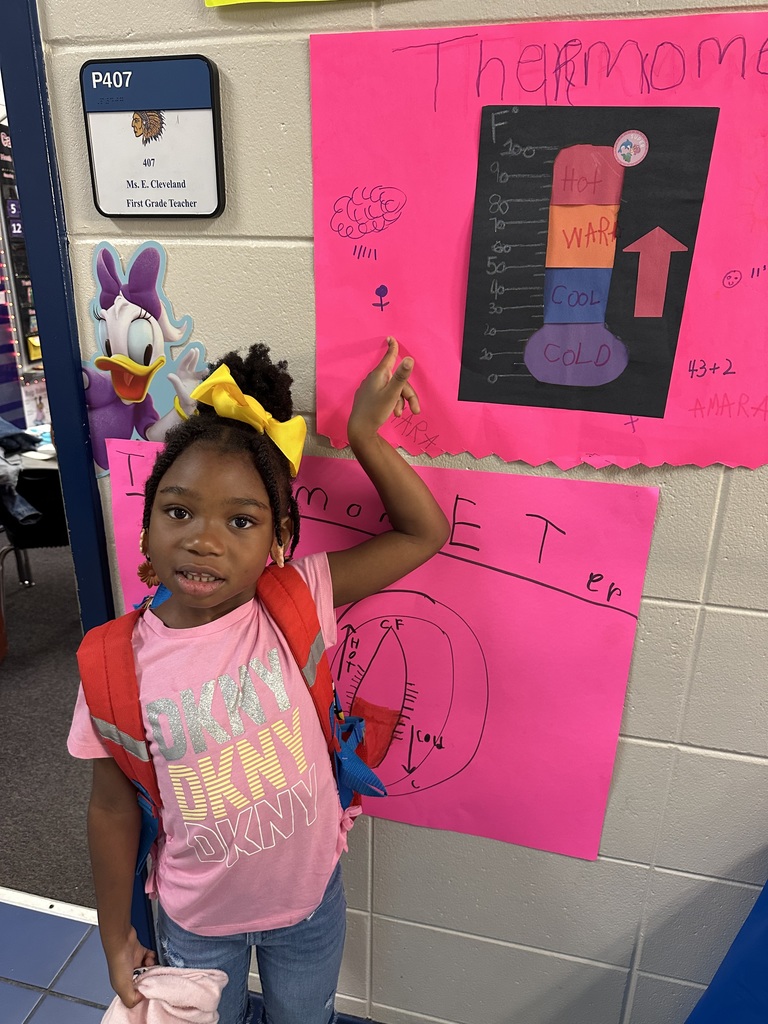 student pointing to her poster on the wall