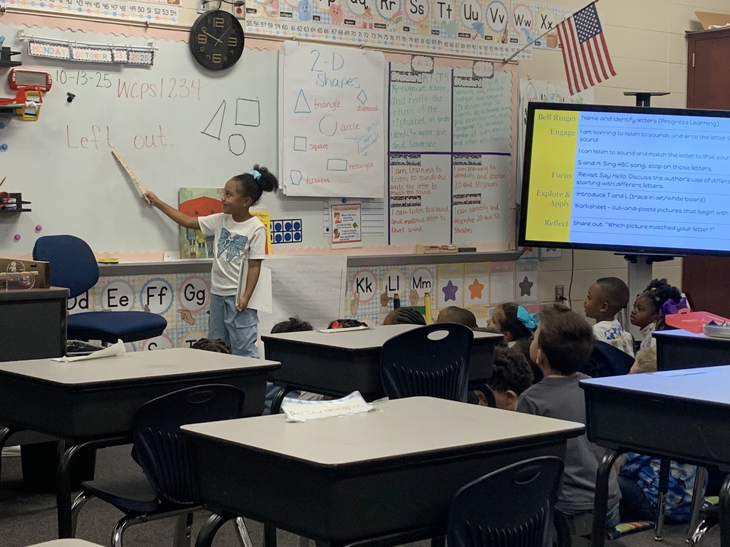 Student pointing out the letters on the board.