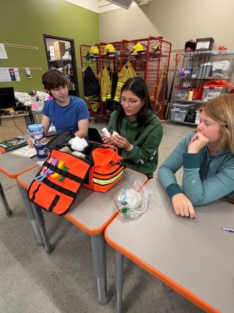 3 students checking EMT bag for inventory