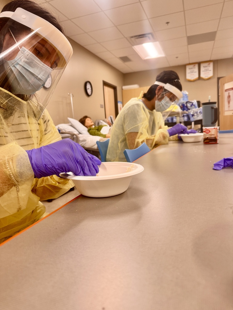 2 students in PPE gear decorating cookies