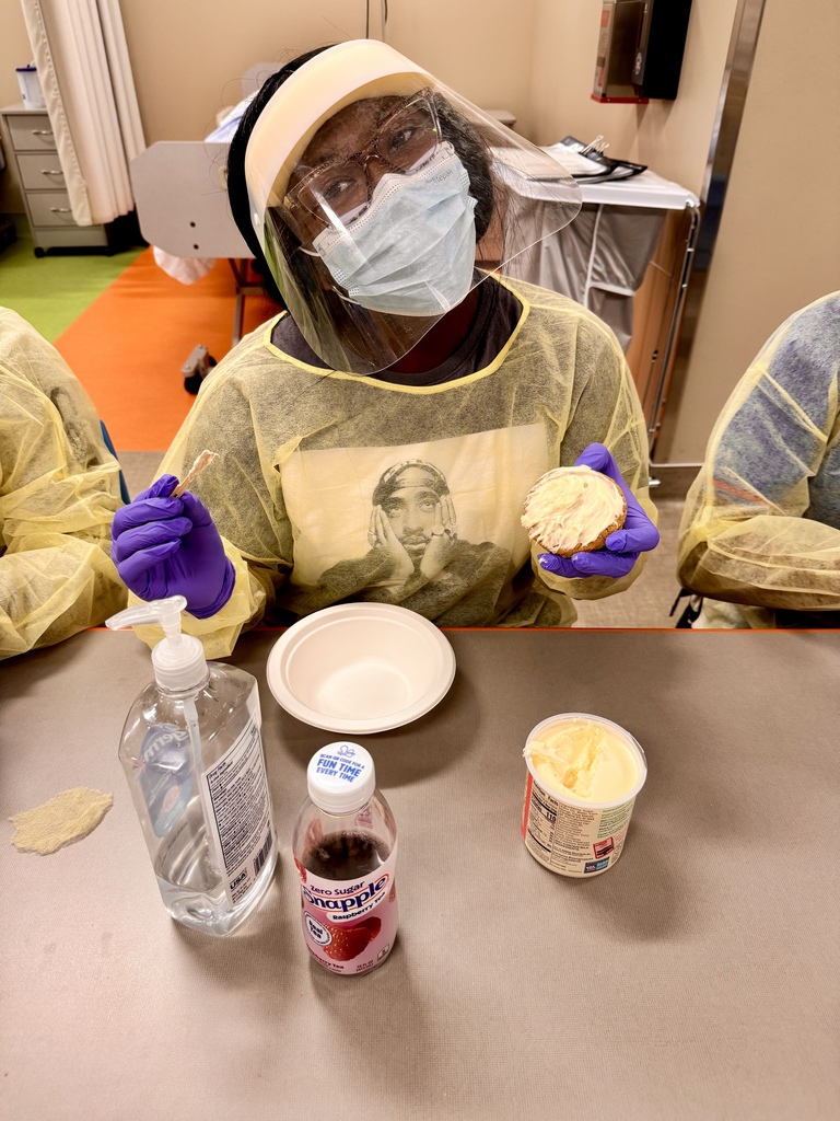 female student in PPE gear decorating cupcake