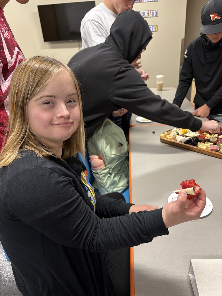 one student sampling food with 3 others in background