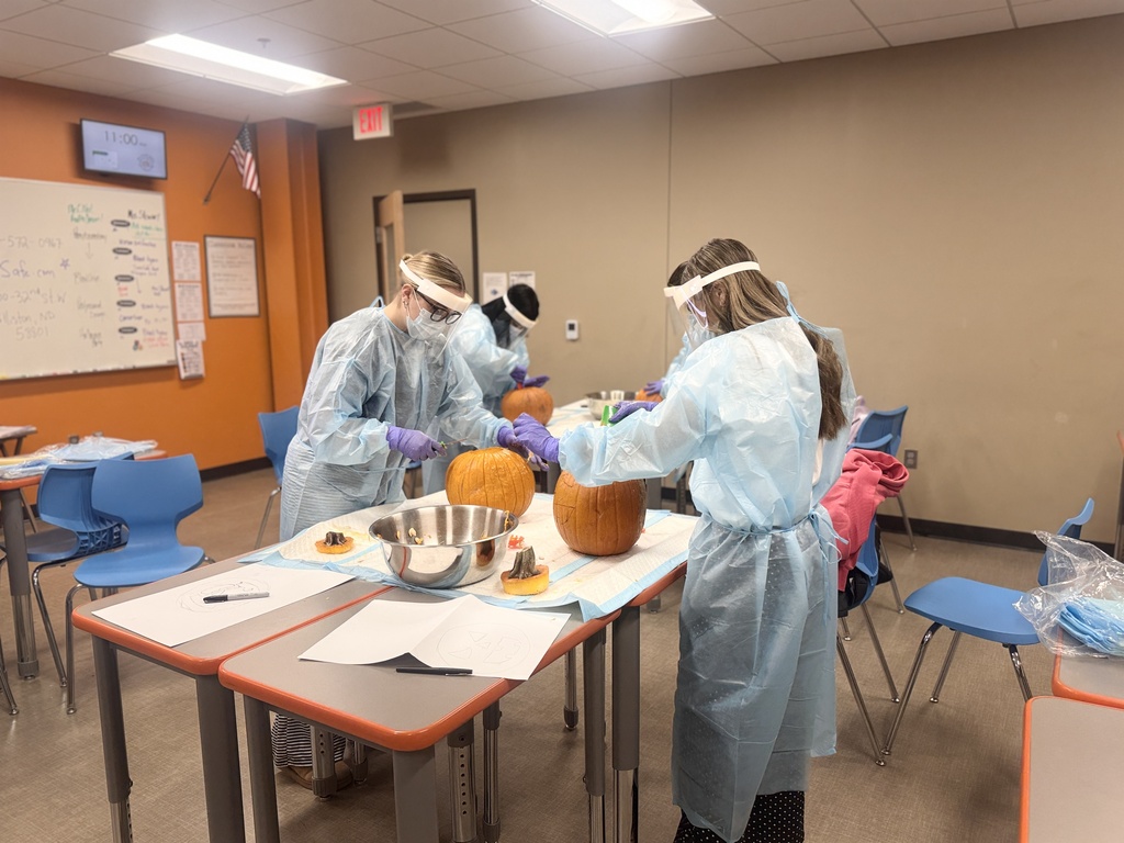 3 students carving pumpkins