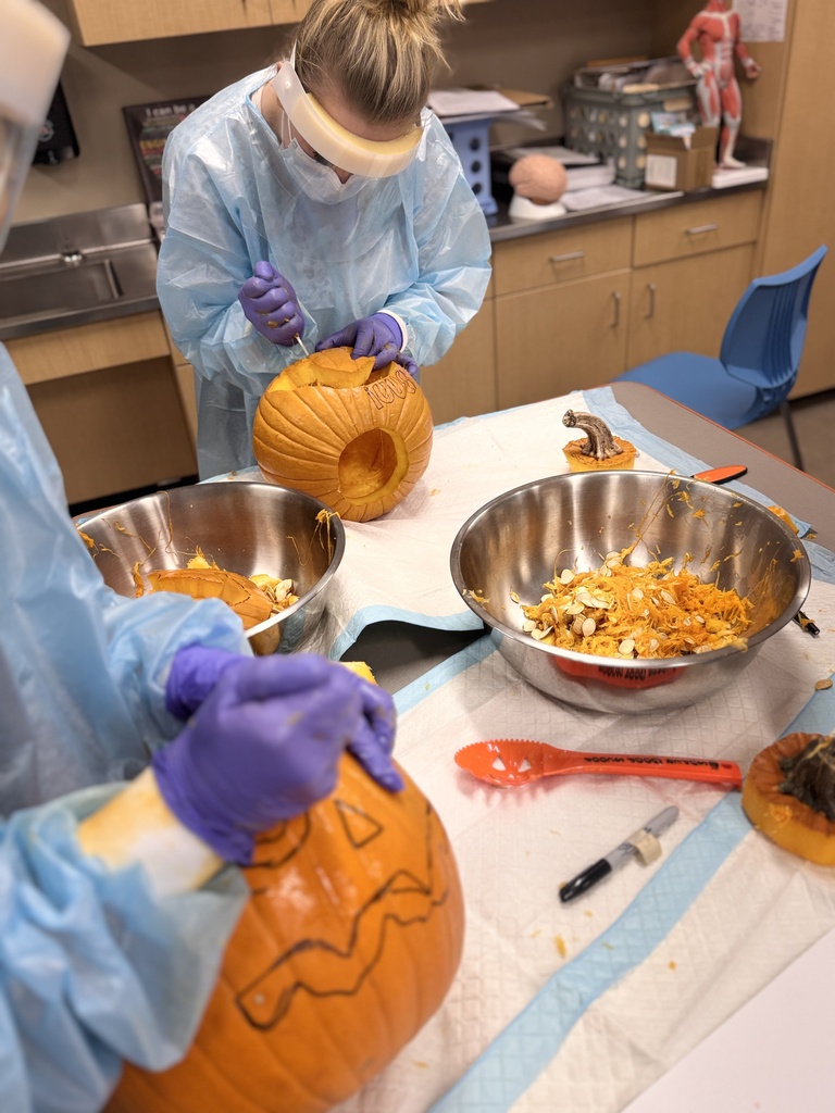 student carving pumpkin
