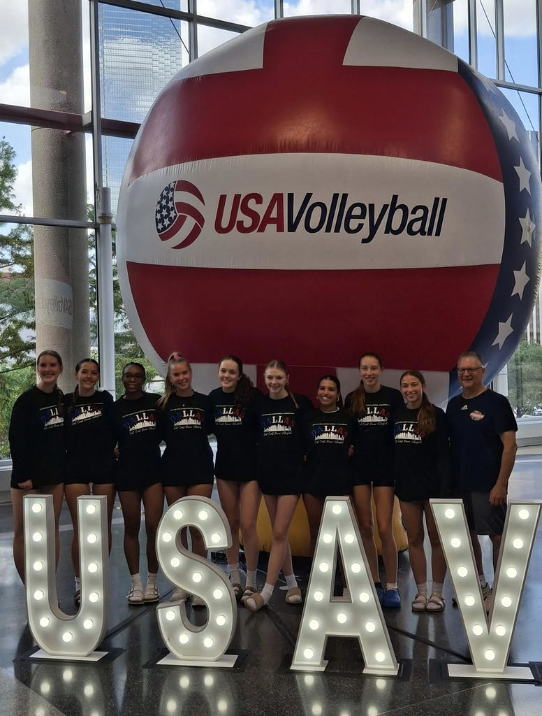 Volleyball Team infront of big volleyball and behind USAV sign