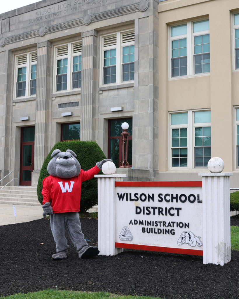 Bulldogs mascot infront of the wilson admin building sign