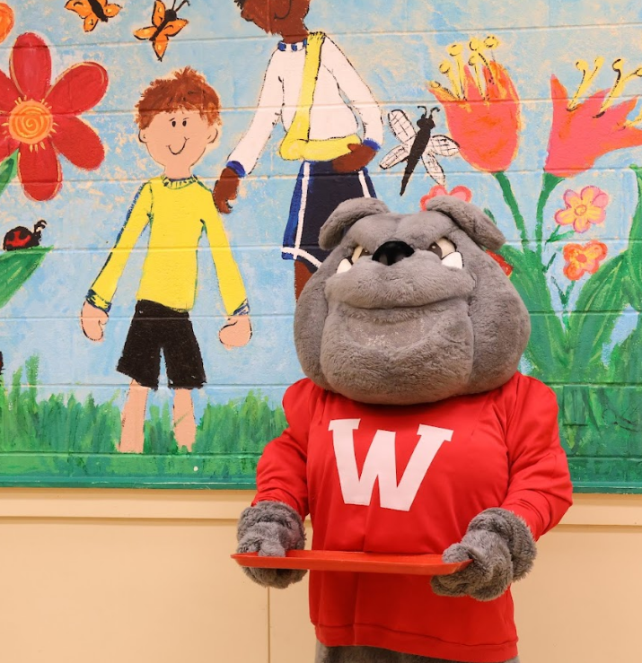Bulldog mascot holding lunch tray in cafeteria