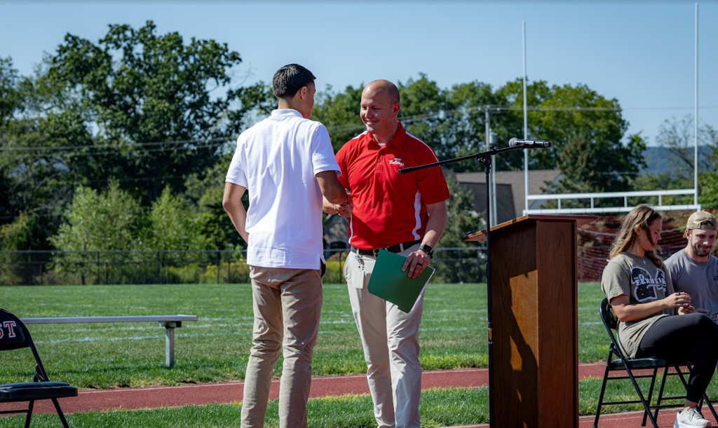 prinicpal shaking hands with student in front of podium