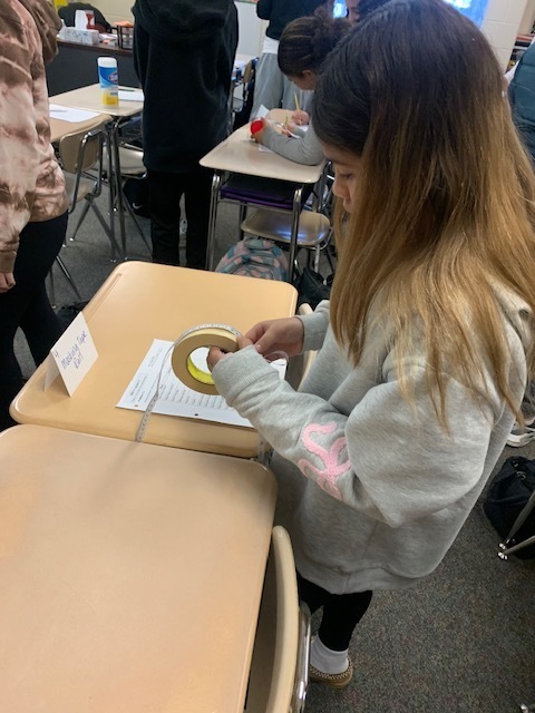 student measuring roll of tape
