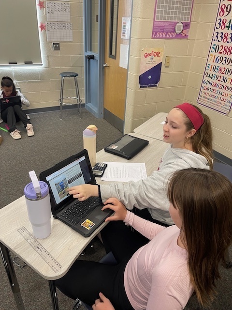 pair of students pointing out what they see on a cromebook