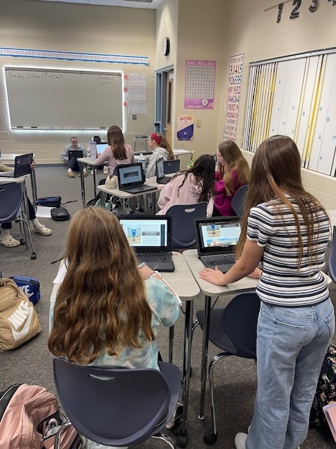 students are seen working in pairs across the room on cromebooks with eachother