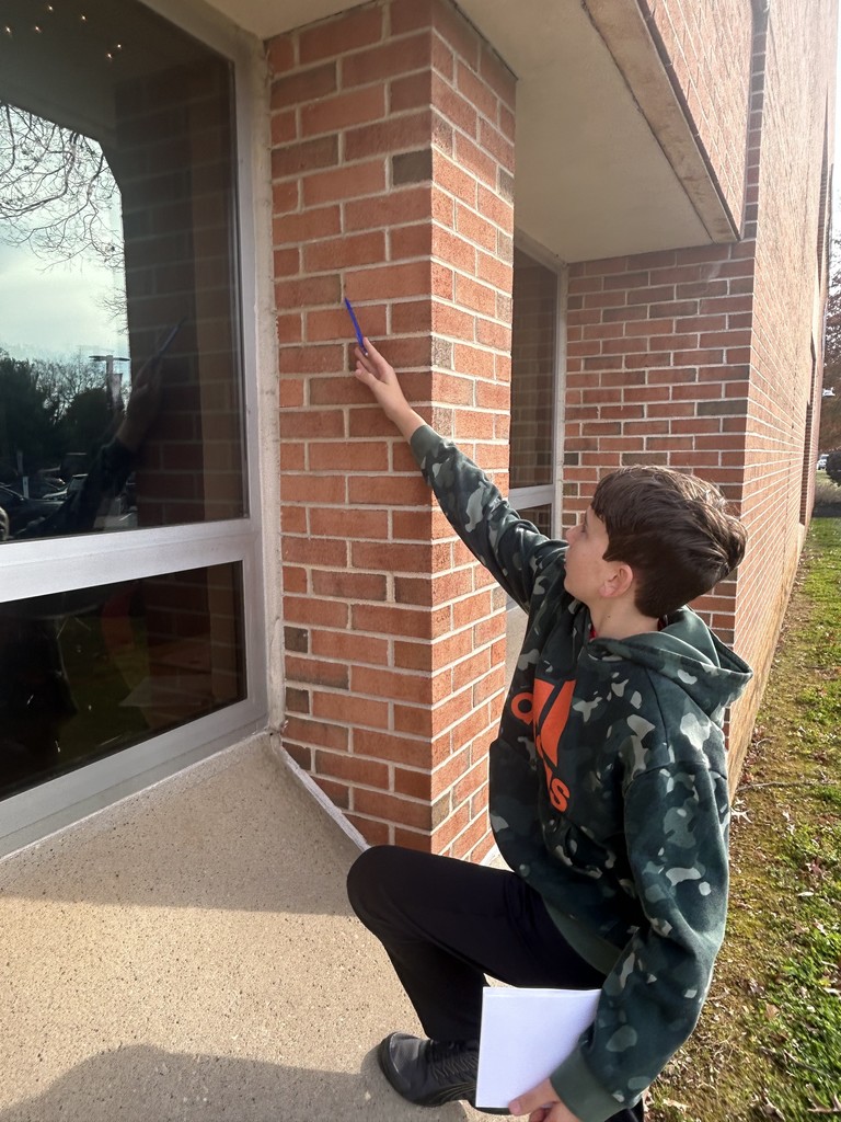 student pointing to something at top of window