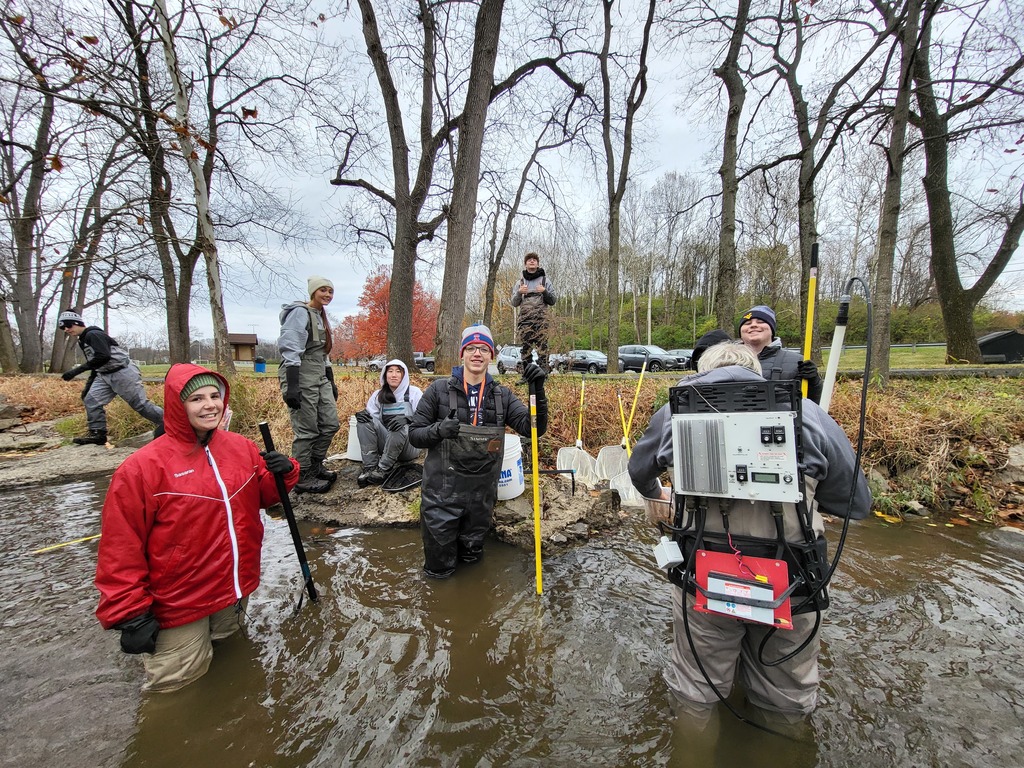 man with backpack that shocks the fish while other kids are standing around him with nets and thumbs up