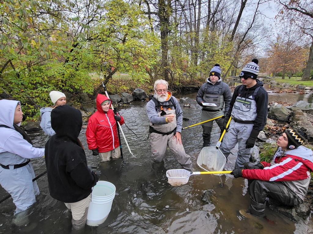man instructing kids in the water while they are holding their nets 