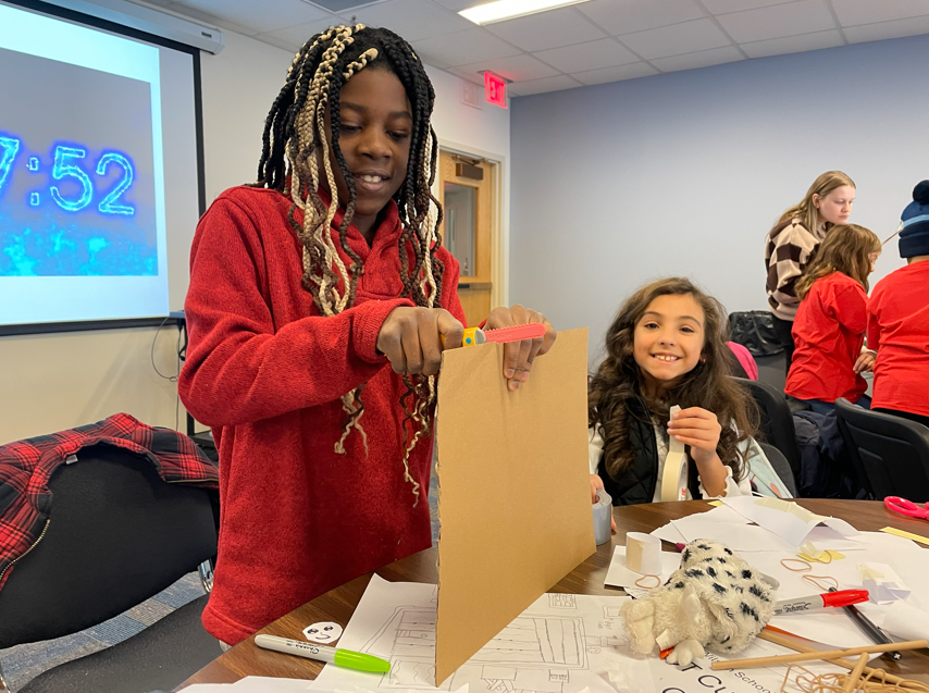 student cutting through cardboard
