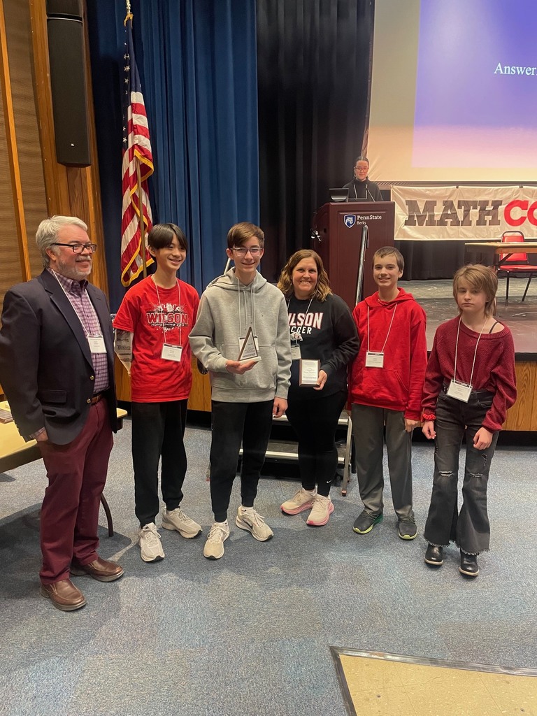 students posing with teacher and award