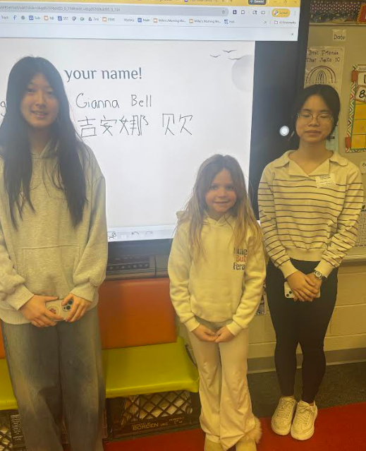 two older girls standing next to a girl with her name written in chinese on the board 