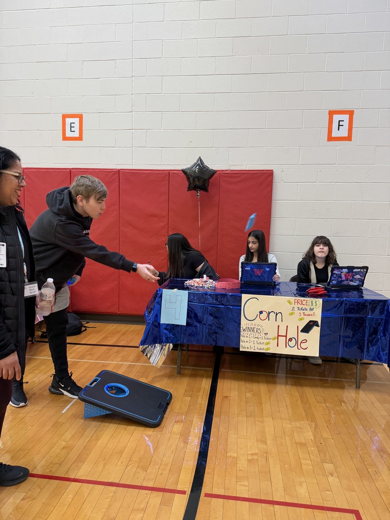 student throwing cornhole bag 
