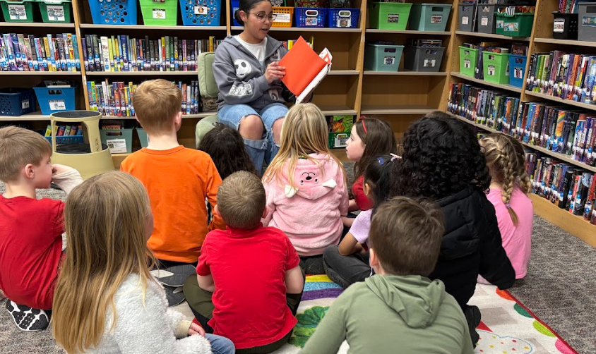 student sitting in front of younger students while reading